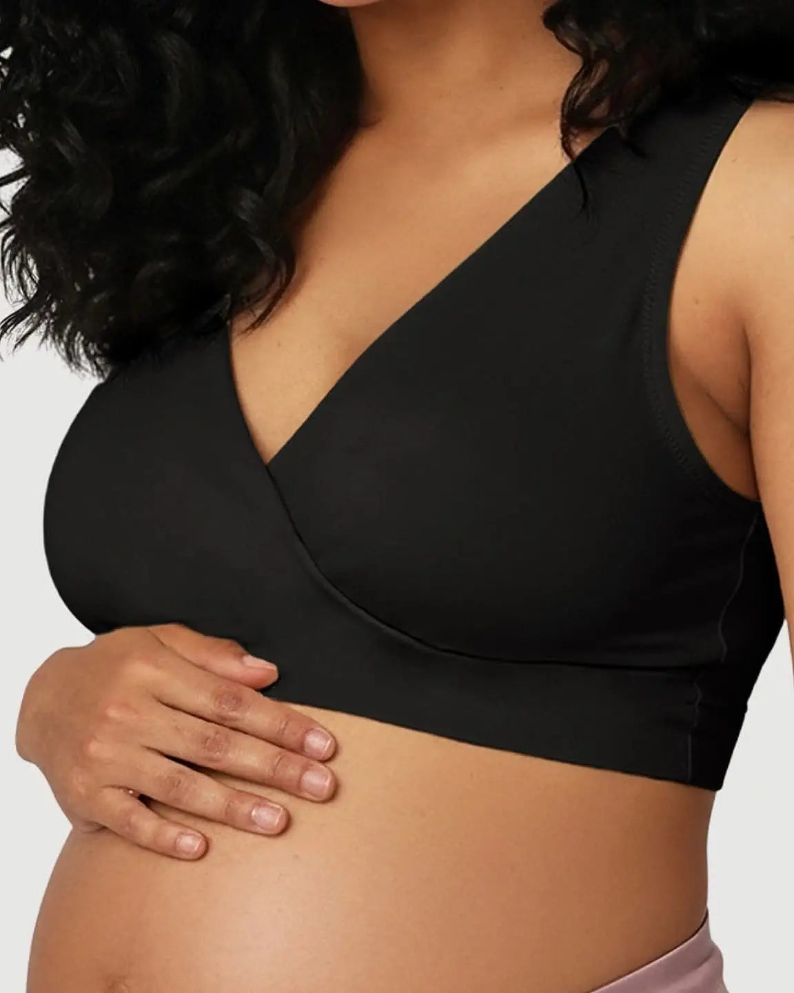 Pregnant woman wearing a black soft cotton wire-free nursing bra with a crossover V-neck design.