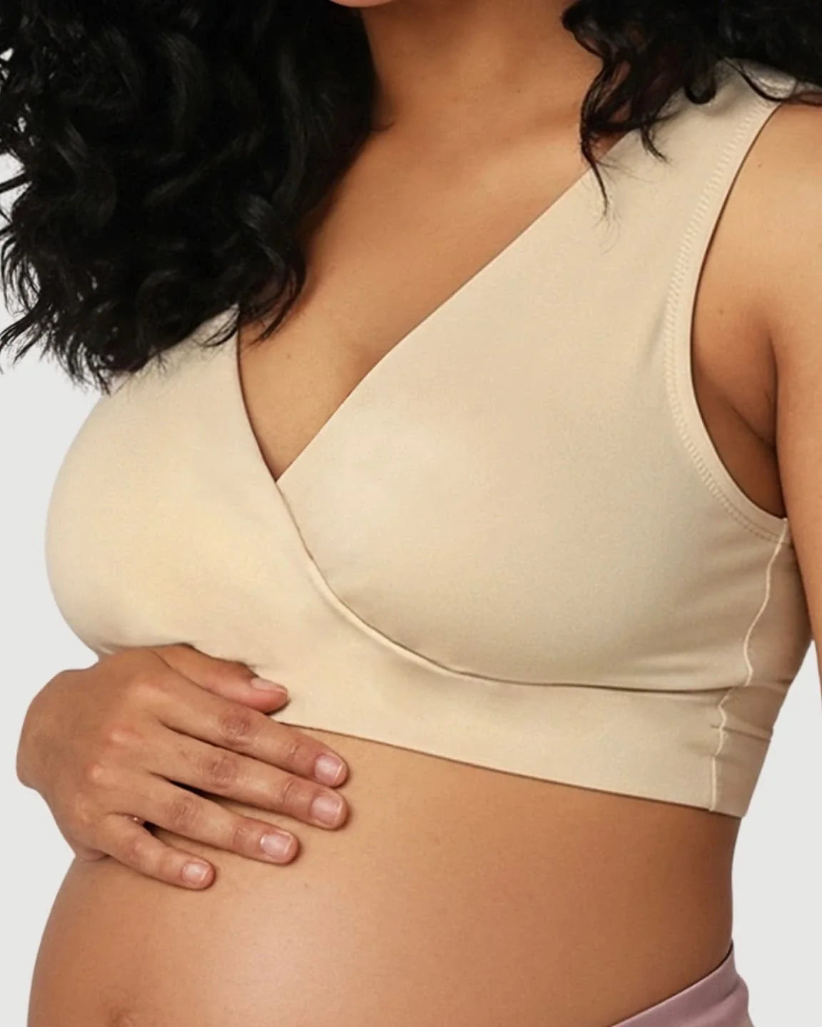 Pregnant woman wearing a soft cotton, wire-free, seamless beige nursing bra with pull-aside cups.