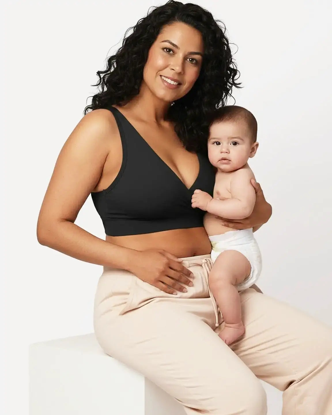 Smiling mother in a black soft cotton wire-free nursing bra holding her baby.