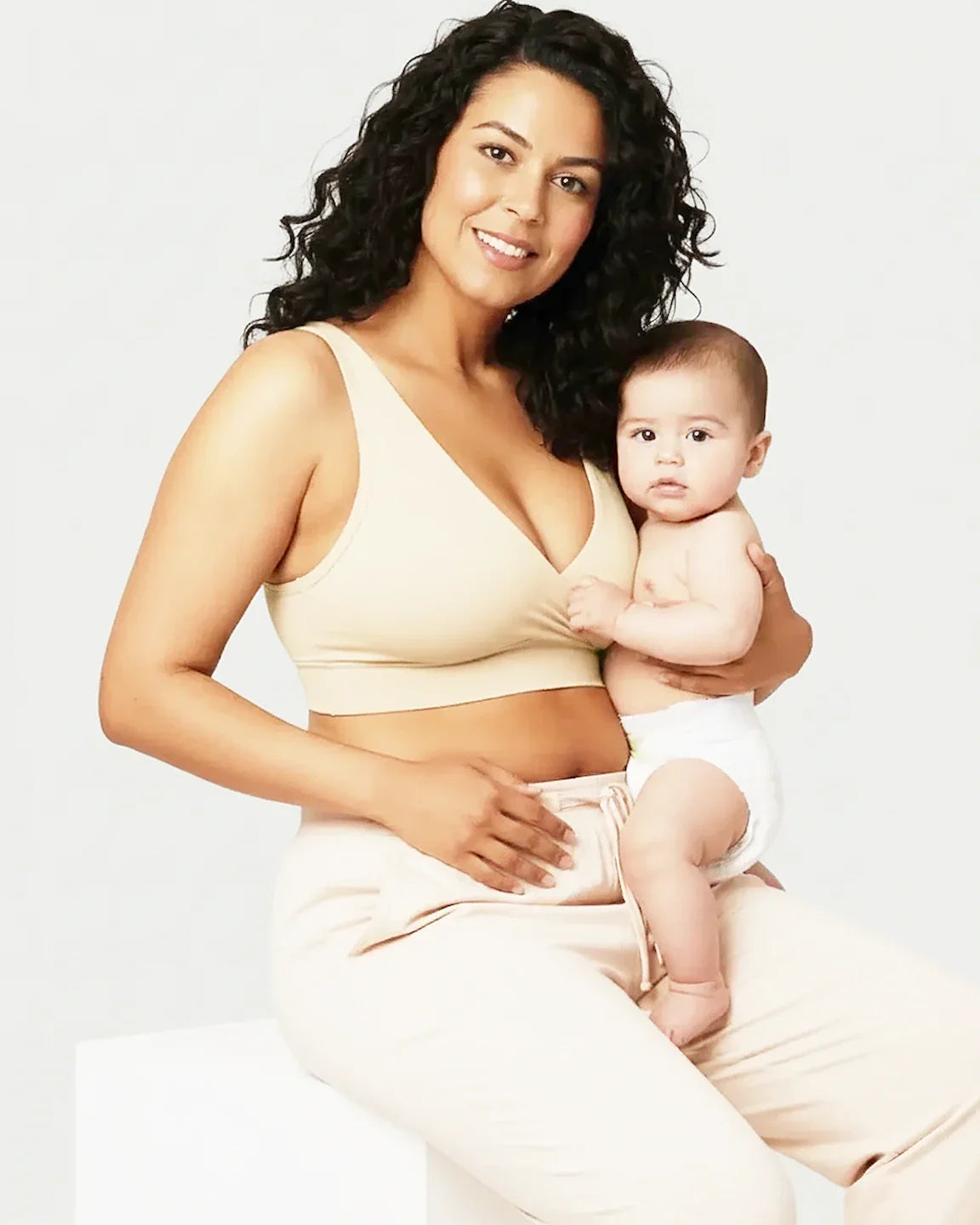 Smiling mother in a beige soft cotton wire-free nursing bra holding her baby.