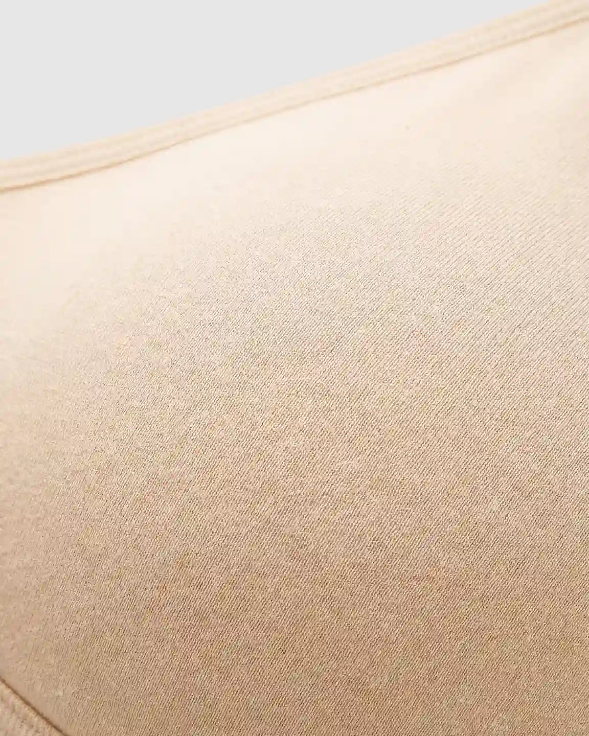 Close-up of a seamless, light beige wireless nursing bra with a soft, stretch-infused fabric texture.
