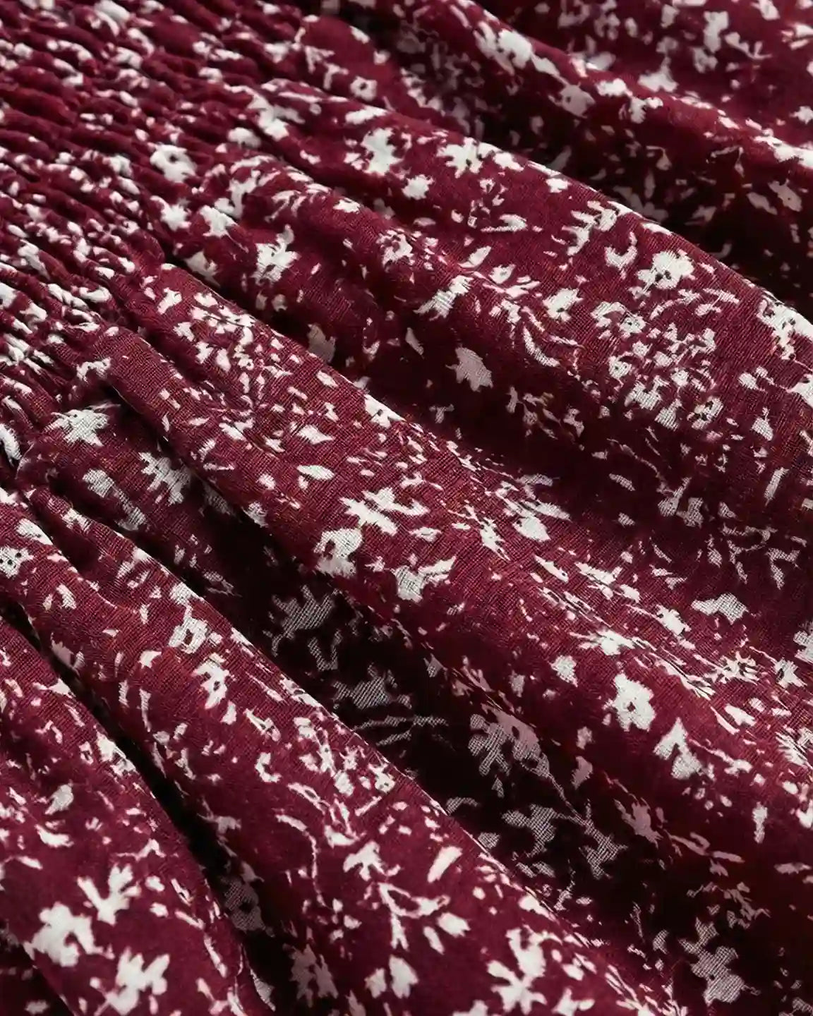 Close-up of a red maternity maxi dress with white floral print and shirred detail.
