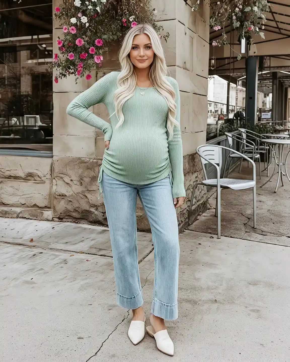 Blonde pregnant woman in a sage green ribbed maternity top with adjustable side drawstrings and light wash jeans.