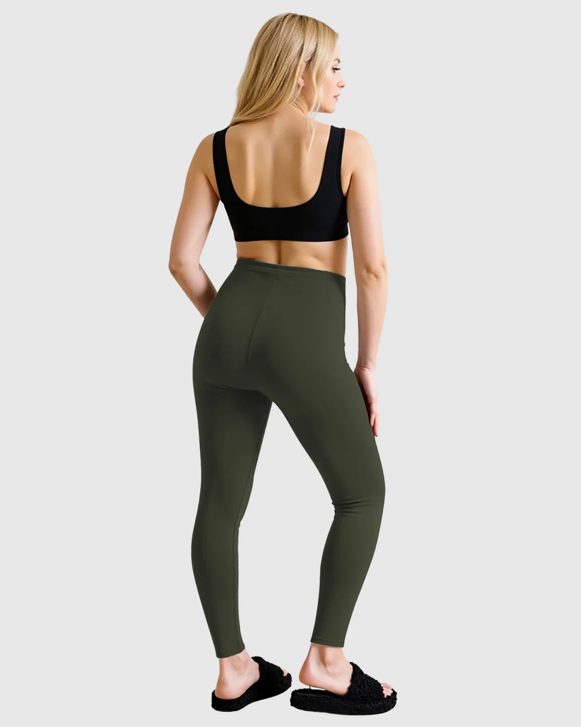 Woman from behind wearing olive green high-waist sculpting maternity leggings and a black sports bra.