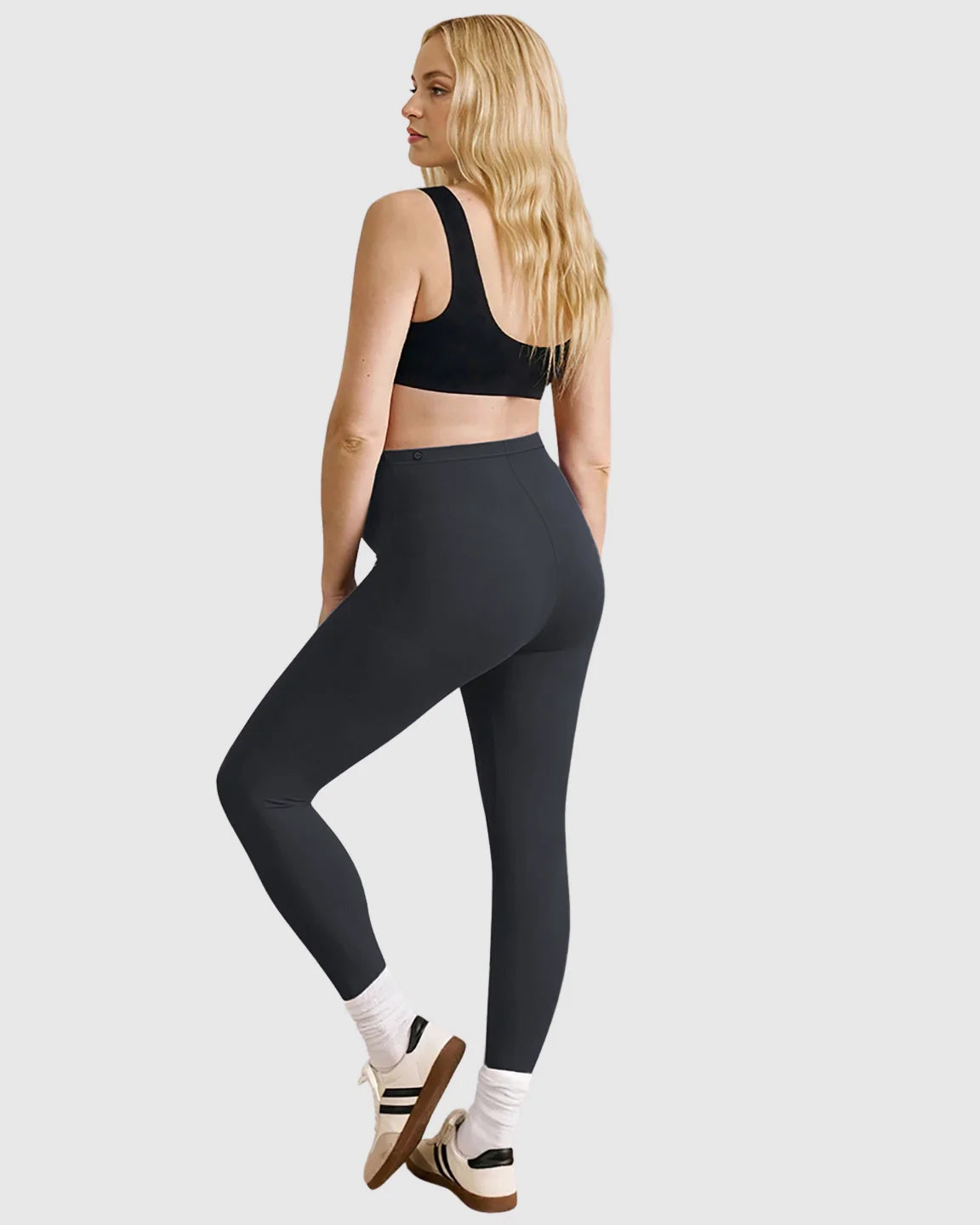 Woman in black Bump Society high-waist sculpting maternity leggings and black sports bra, viewed from behind.