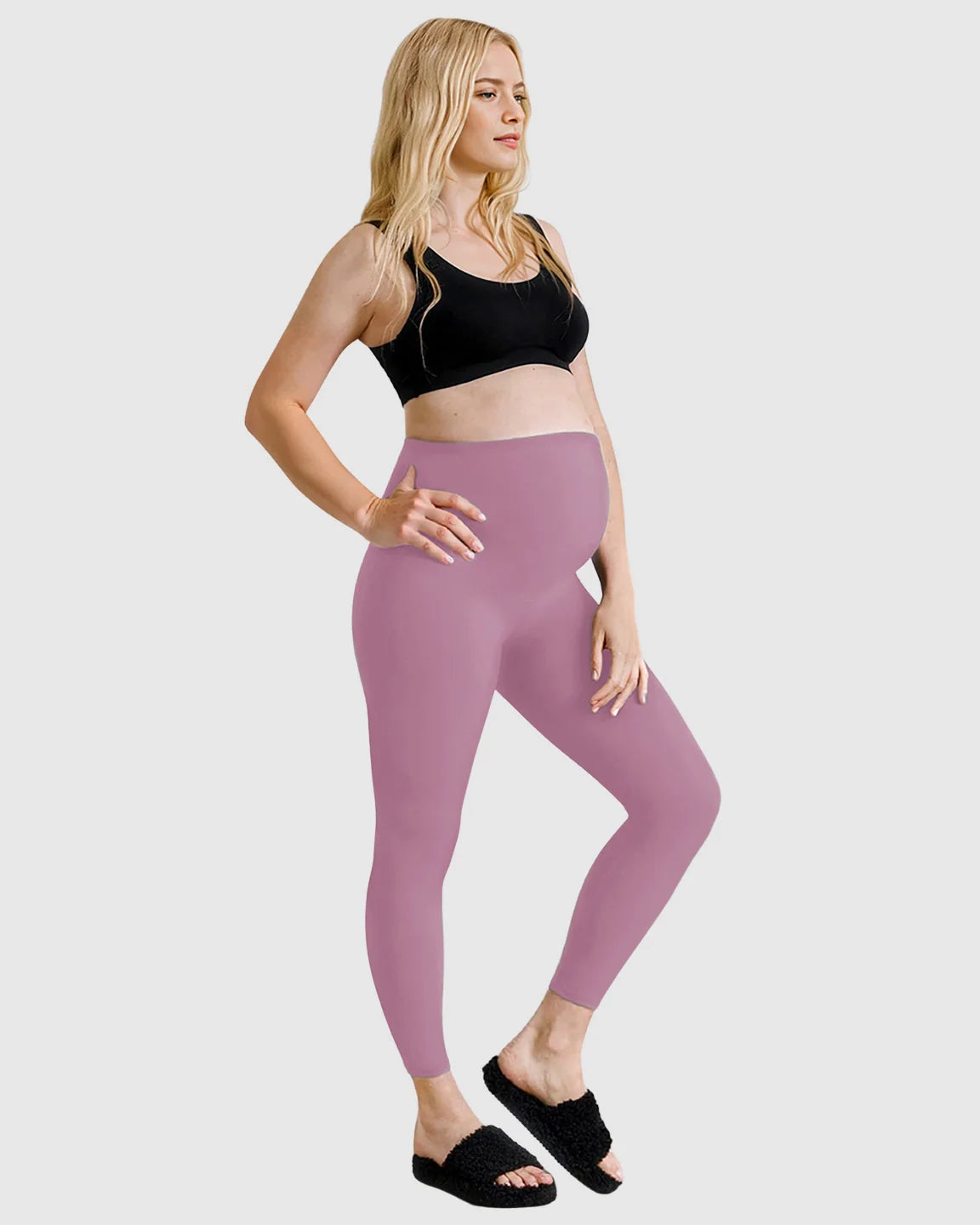 Blonde pregnant woman in a black sports bra and high-waist mauve sculpting maternity leggings.