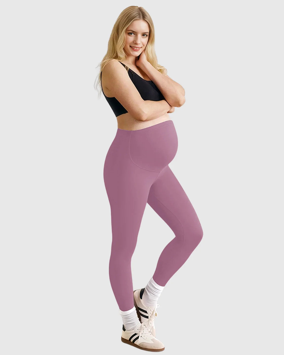 Smiling pregnant woman in high-waist mauve sculpting maternity leggings and a black sports bra.