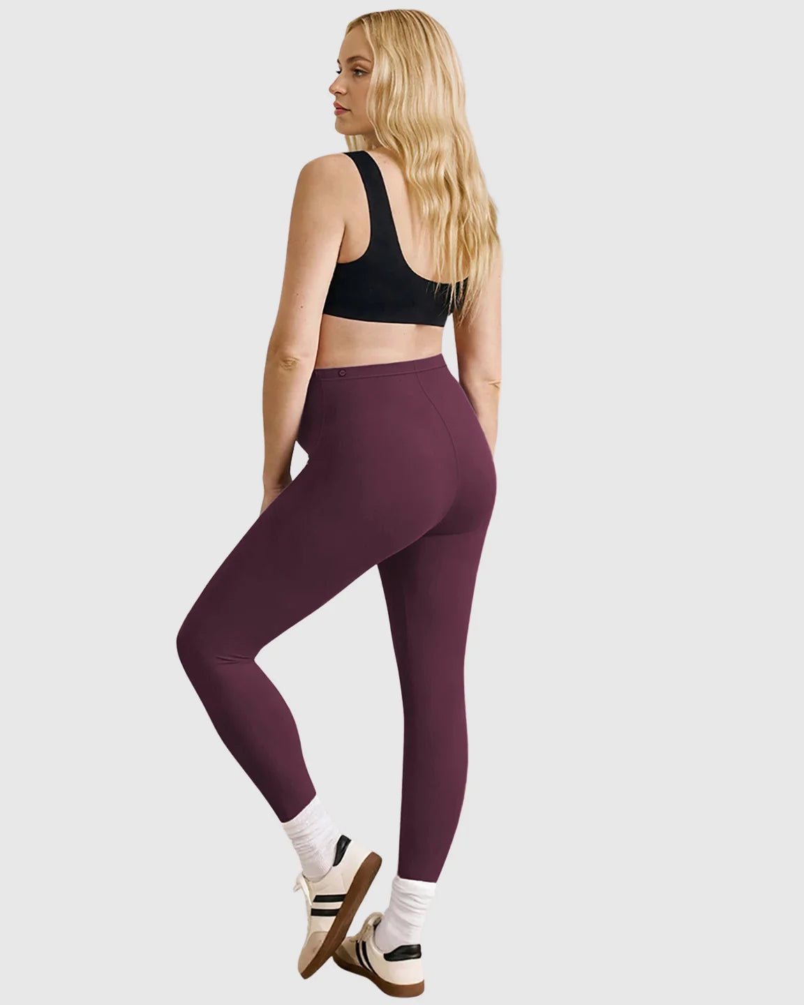 Woman from behind wearing plum high-waist sculpting maternity leggings and a black sports bra.
