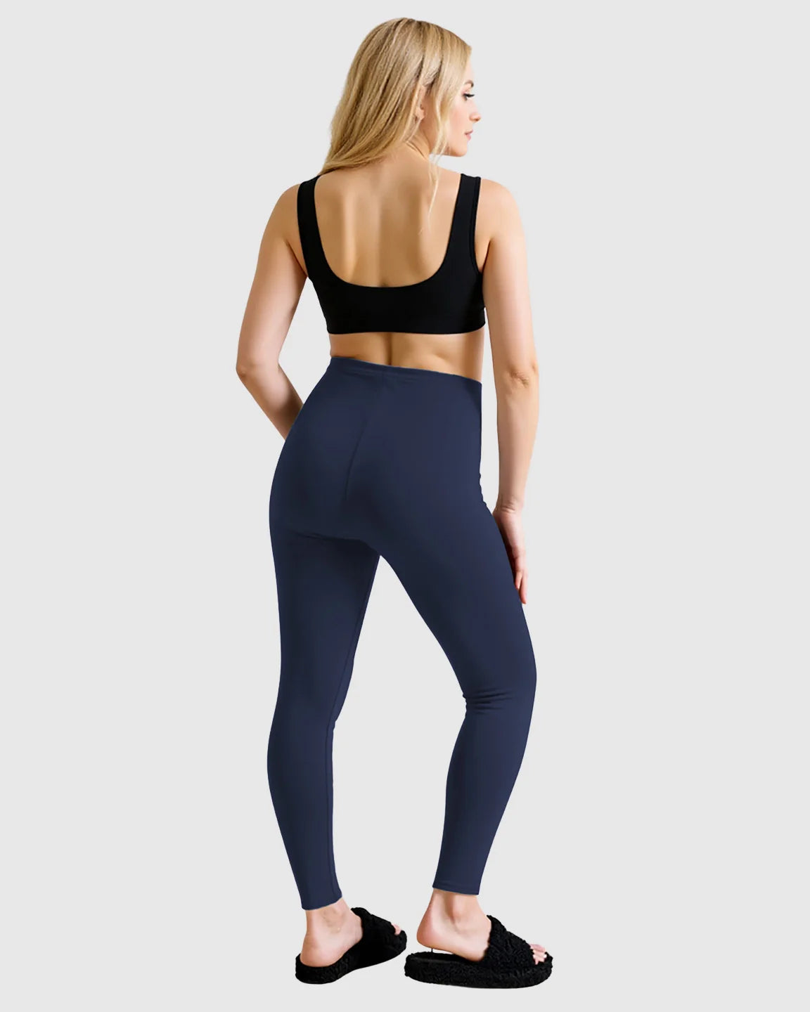 Blonde woman from behind wearing navy high-waist sculpting maternity leggings and a black sports bra.