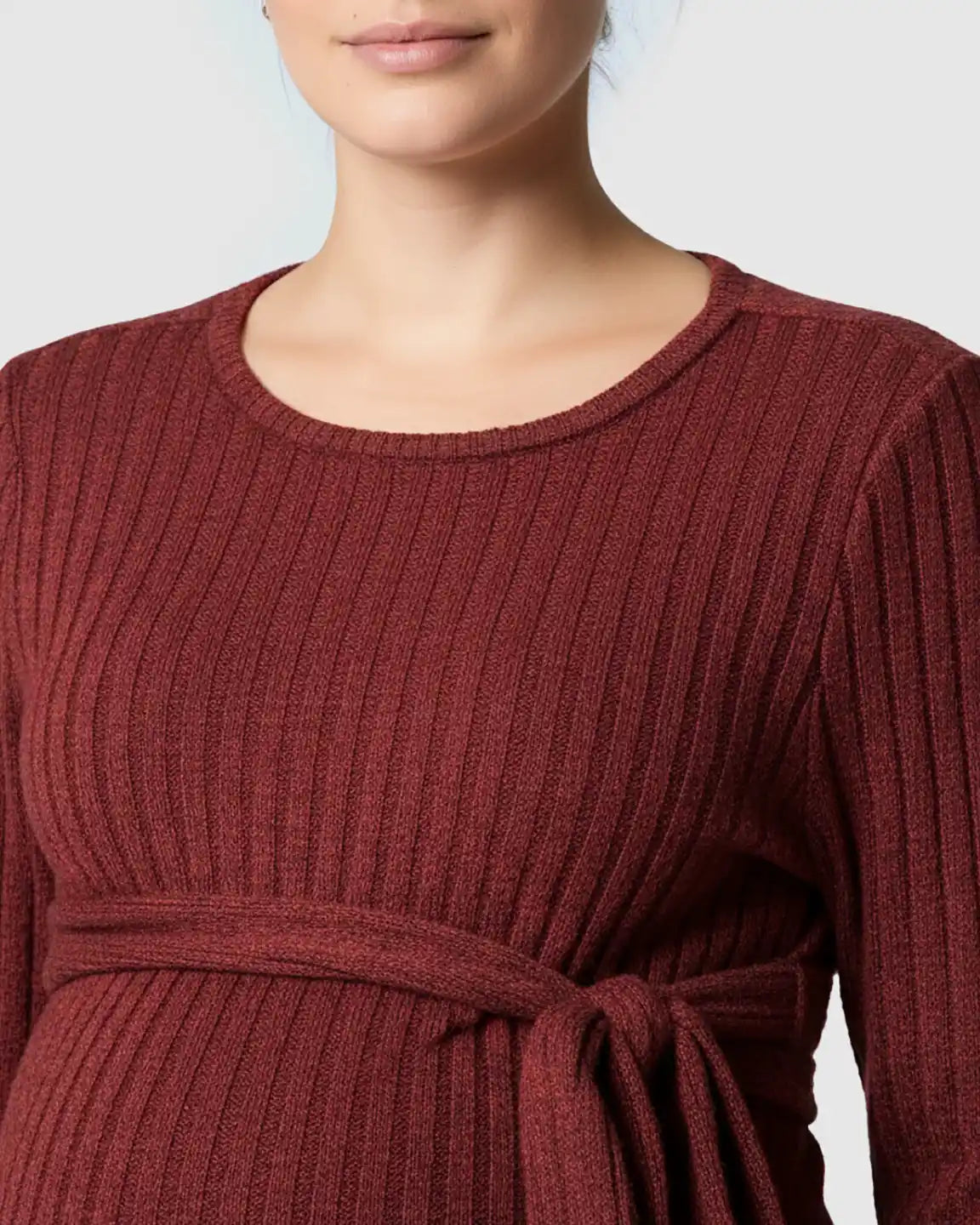 Close-up of a pregnant woman wearing a red ribbed long-sleeve maternity sweater with a tie-waist.