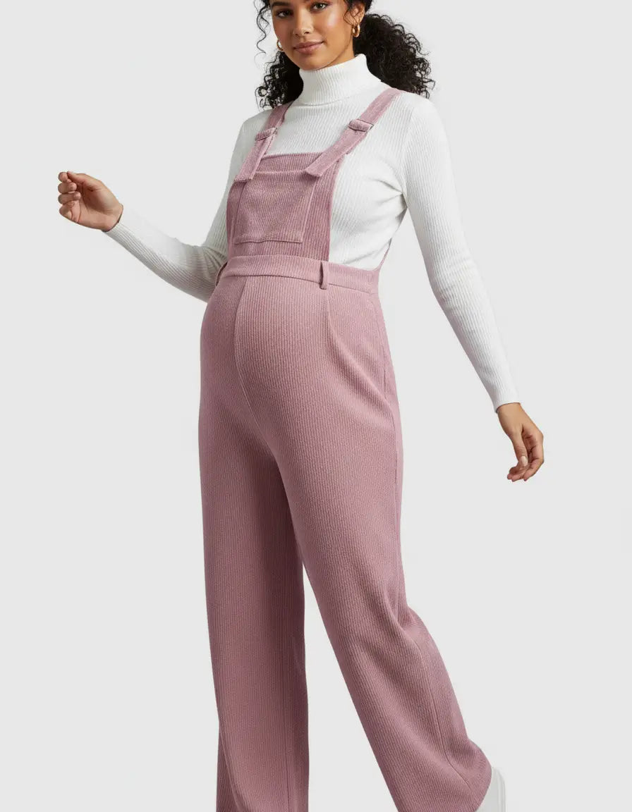 Woman in a pink corduroy maternity jumpsuit with adjustable straps and a white turtleneck.