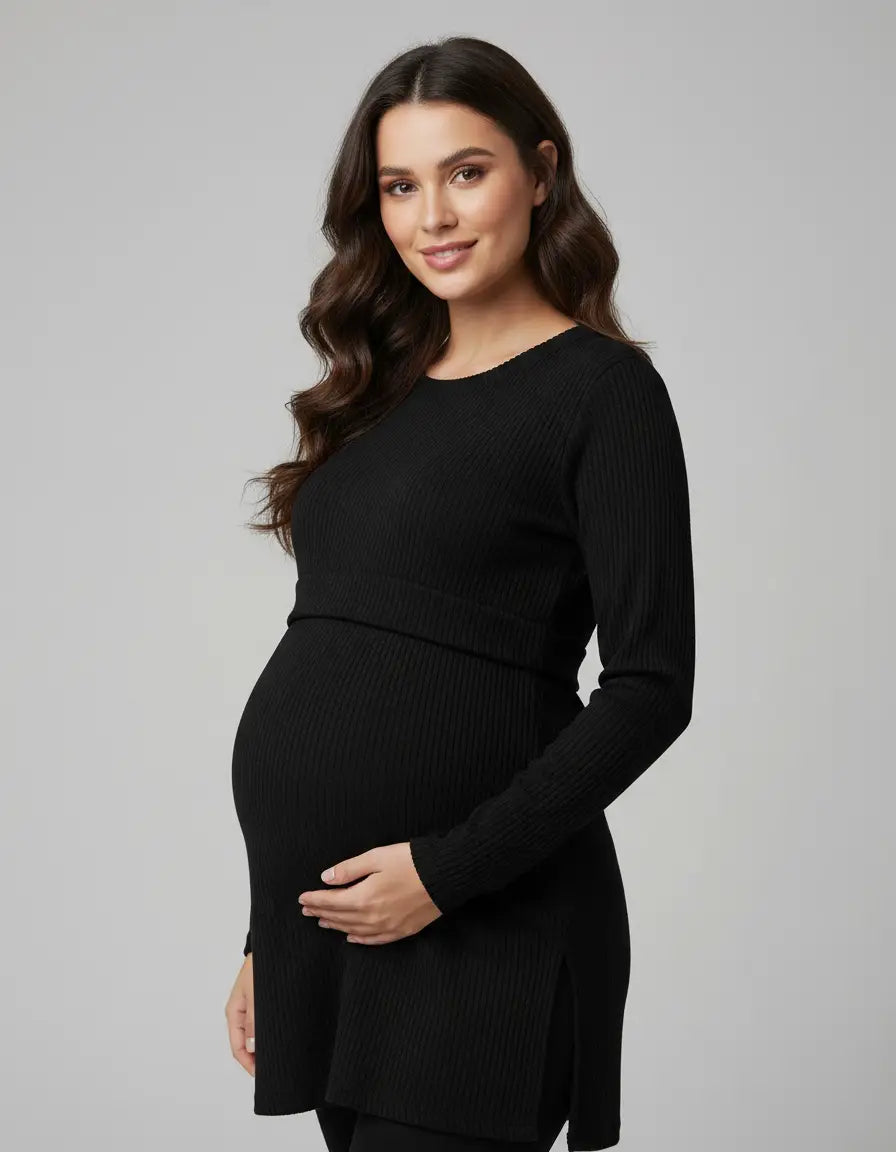 Pregnant woman in a black ribbed long-sleeve maternity top with side slits, gently cradling her bump.
