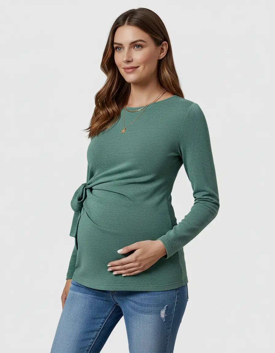 Pregnant woman in a green, long-sleeve, slim-fit maternity top with an adjustable side-tie.