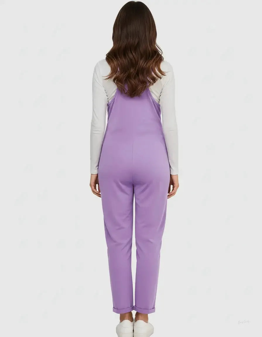 Woman from behind wearing a flowy lavender maternity jumpsuit with adjustable straps over a white long-sleeve shirt.