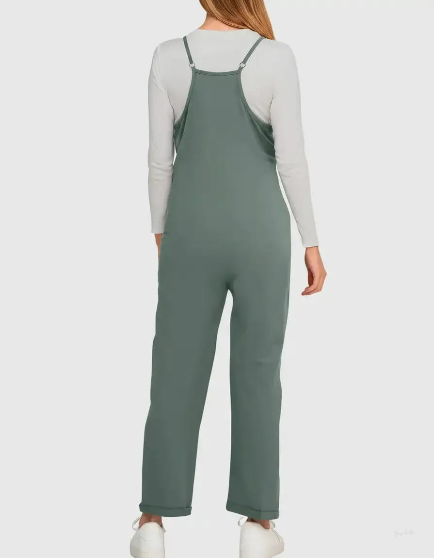 Sage green flowy maternity jumpsuit with adjustable straps, worn over a white long-sleeve top.