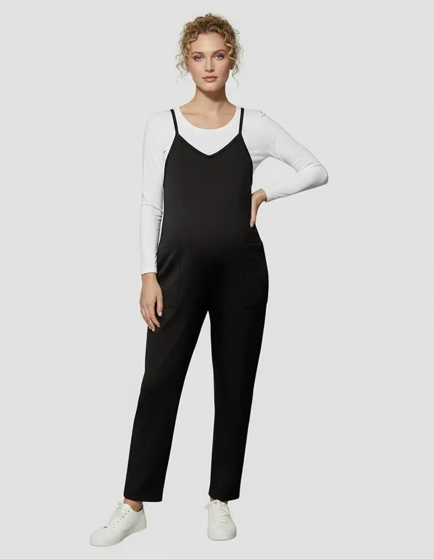 Black flowy maternity jumpsuit with adjustable straps, worn over a white long-sleeve top.