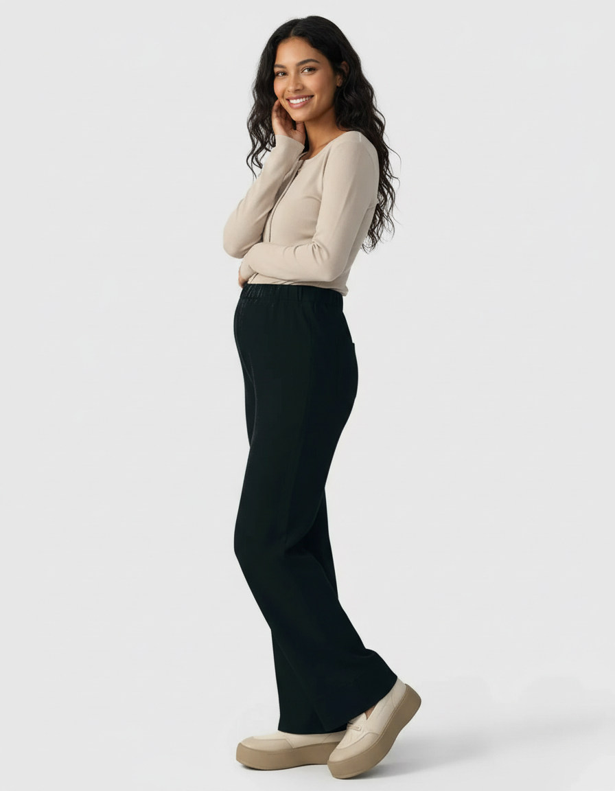 Smiling pregnant woman in black wide-leg maternity pants and a beige long-sleeve top.