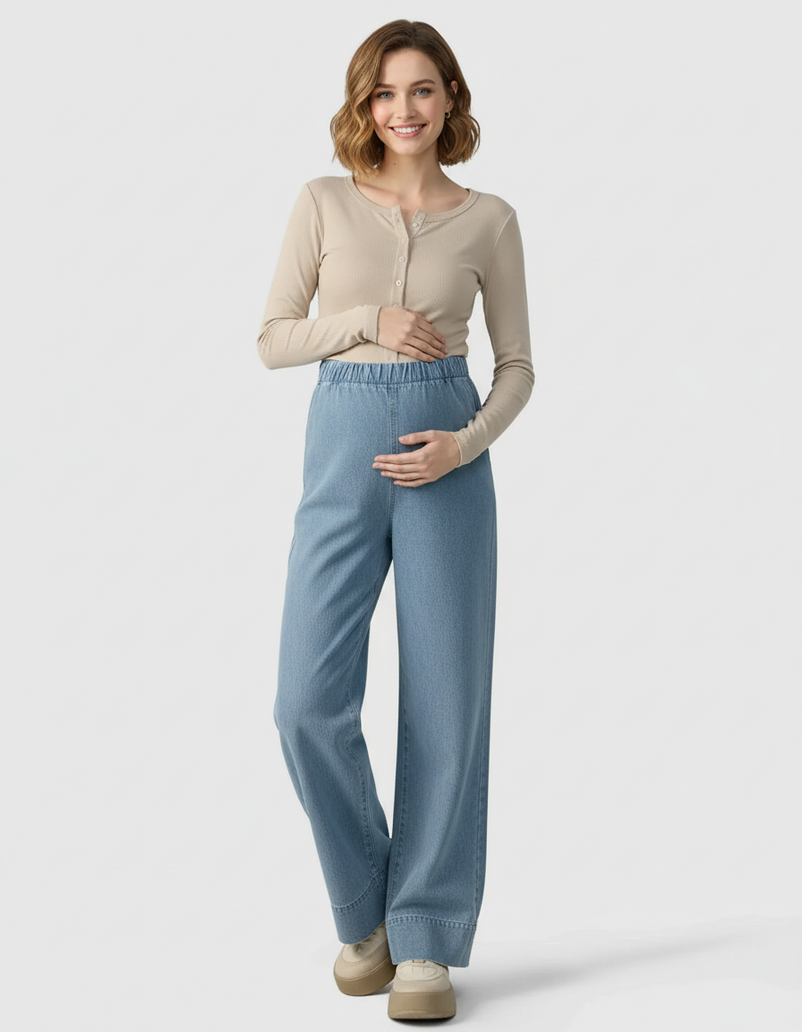 Smiling pregnant woman in light wash wide-leg maternity denim pants and a beige ribbed top.