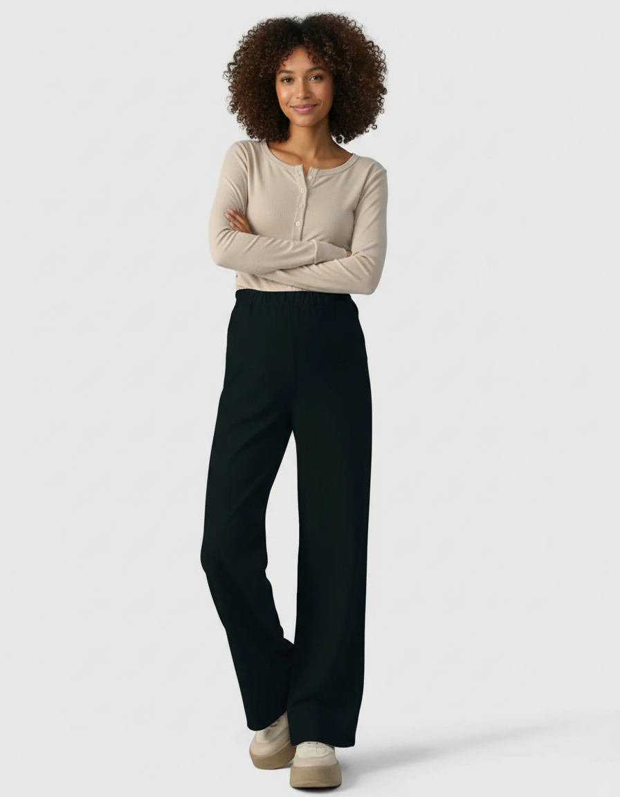 Smiling woman in black wide-leg maternity denim pants with an adjustable waist, paired with a beige long-sleeve top.
