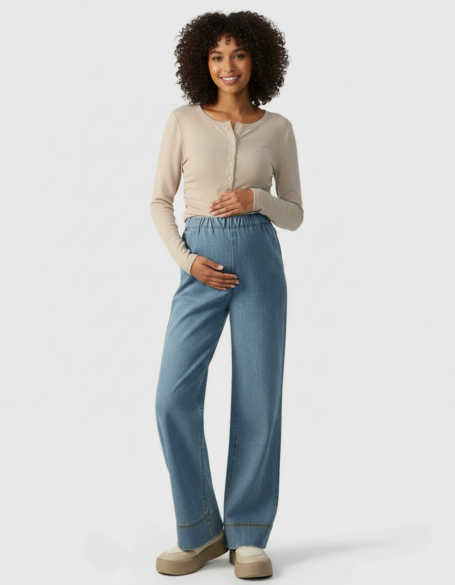 Smiling pregnant woman in light wash wide-leg maternity denim pants with an elastic waist and a beige long-sleeve top.