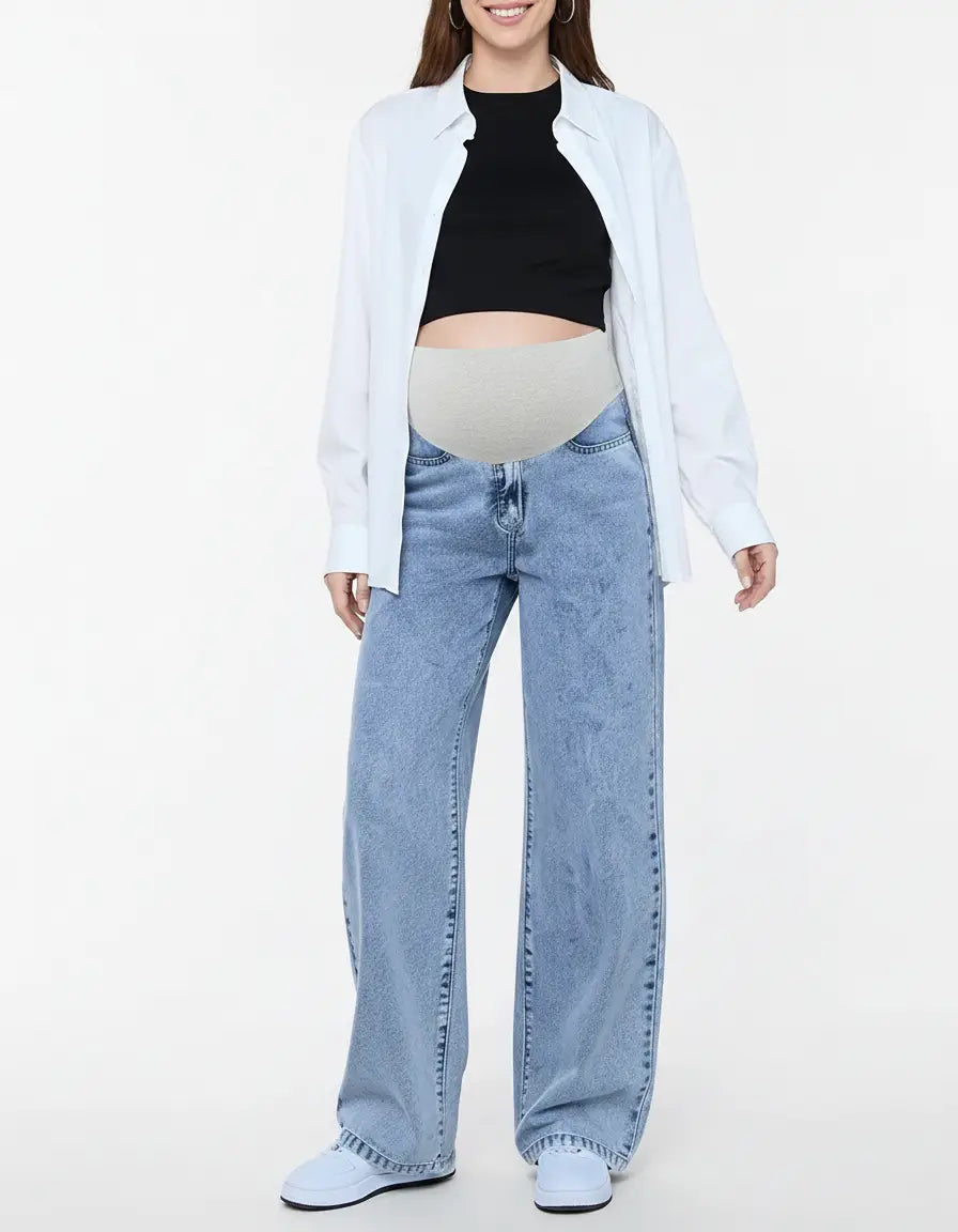 Woman wearing light wash wide-leg maternity jeans with a grey adjustable waistband, black top, and white shirt.