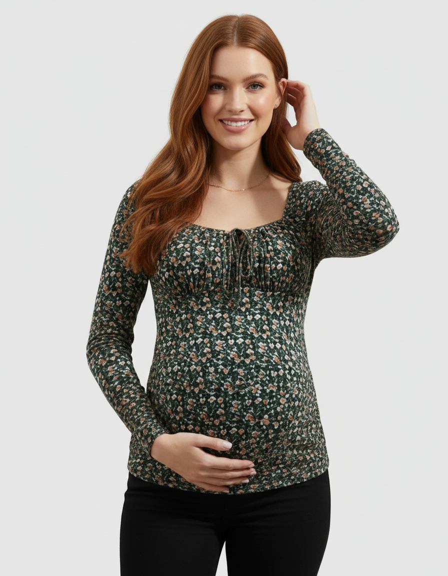 Smiling pregnant woman in a dark green floral ruched tie-front long-sleeve maternity top.