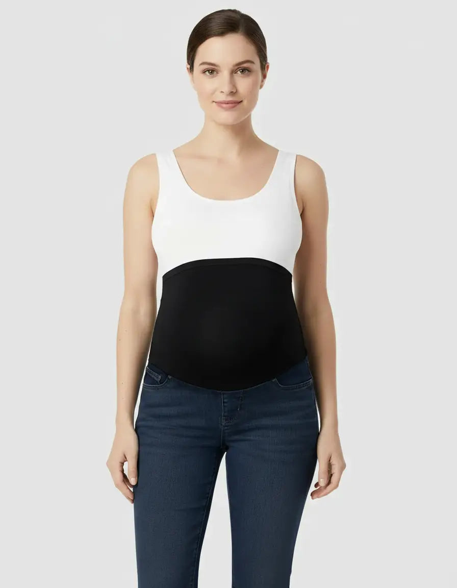 Woman wearing dark wash, high-waist flared-leg maternity jeans with a black over-belly panel and white tank top.