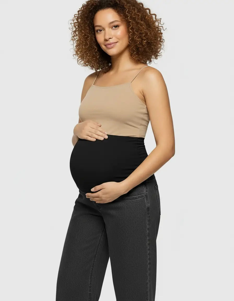 Smiling pregnant woman in a beige camisole and black wide-leg maternity jeans with an elastic waist.