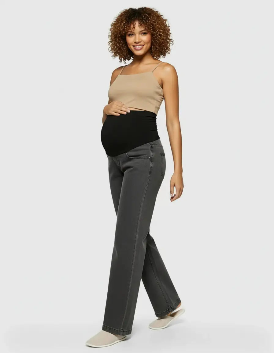 Smiling pregnant woman in charcoal wide-leg maternity jeans with a black elastic waist and a beige camisole.