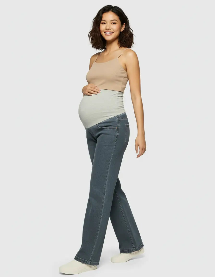 Smiling pregnant woman in dark wash wide-leg maternity jeans with a light grey elastic belly band.