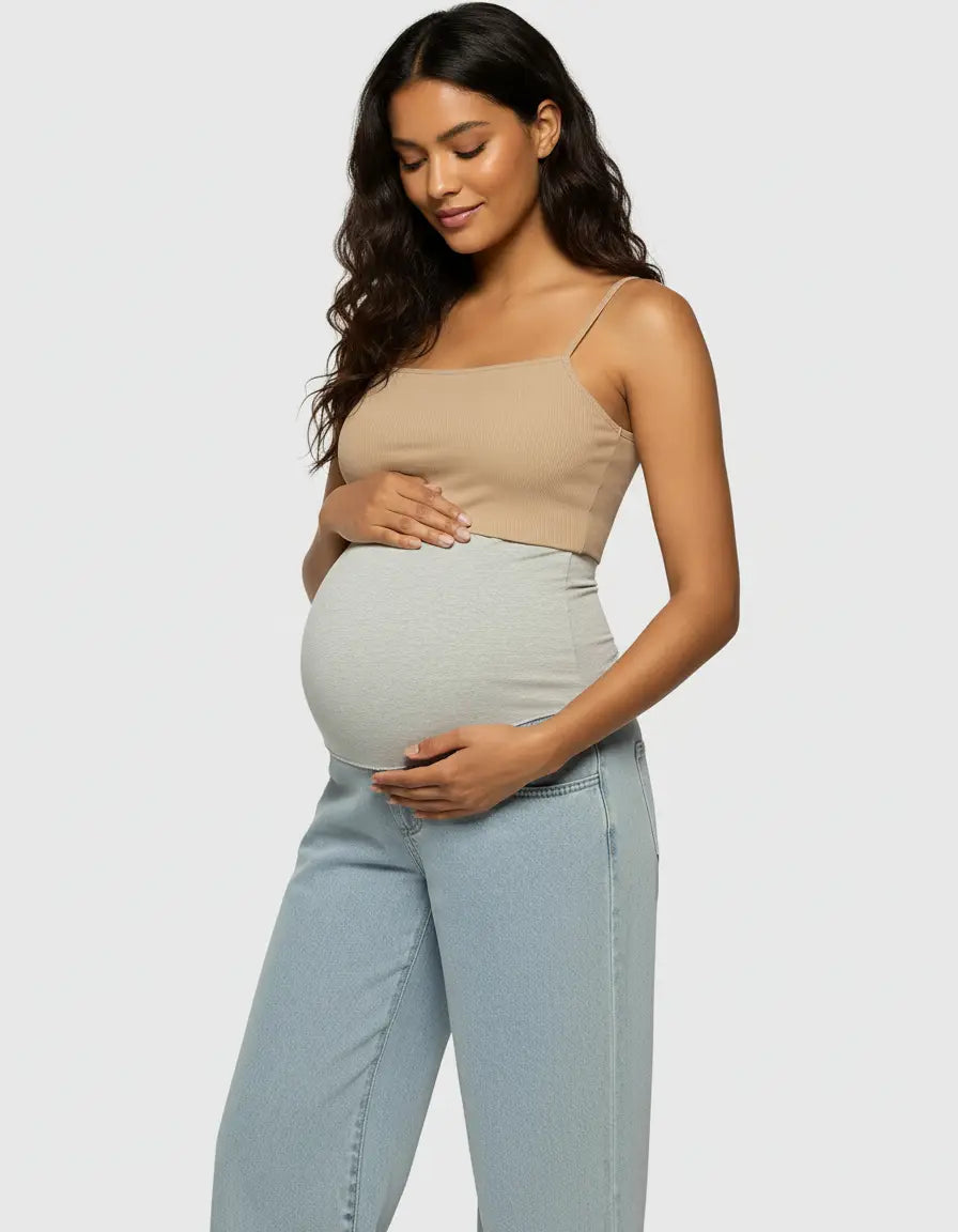 Pregnant woman in light wash wide-leg maternity jeans with a grey elastic waist and a beige crop top.