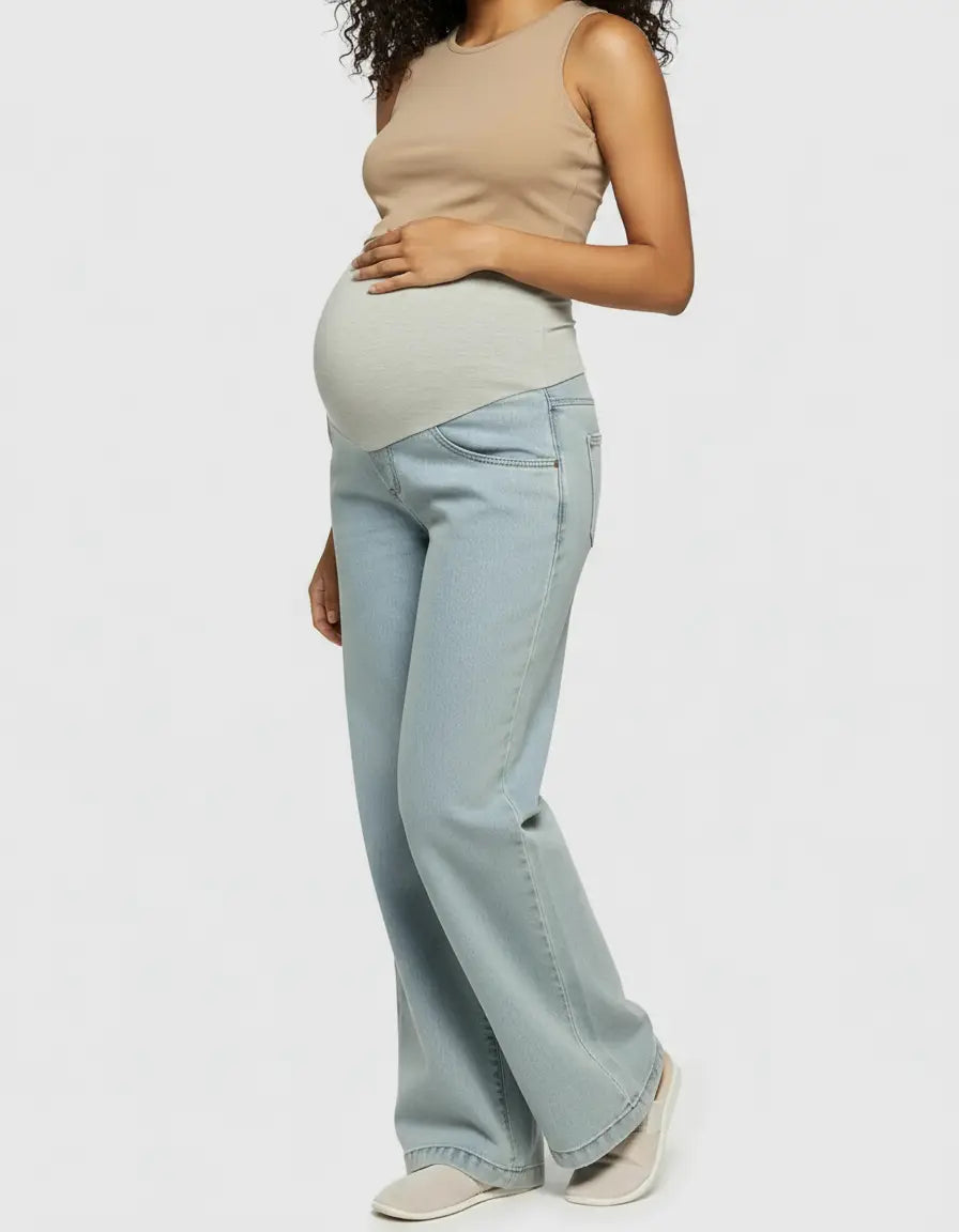 Maternity model wearing light wash wide-leg jeans with a soft elastic belly band and a beige tank top.