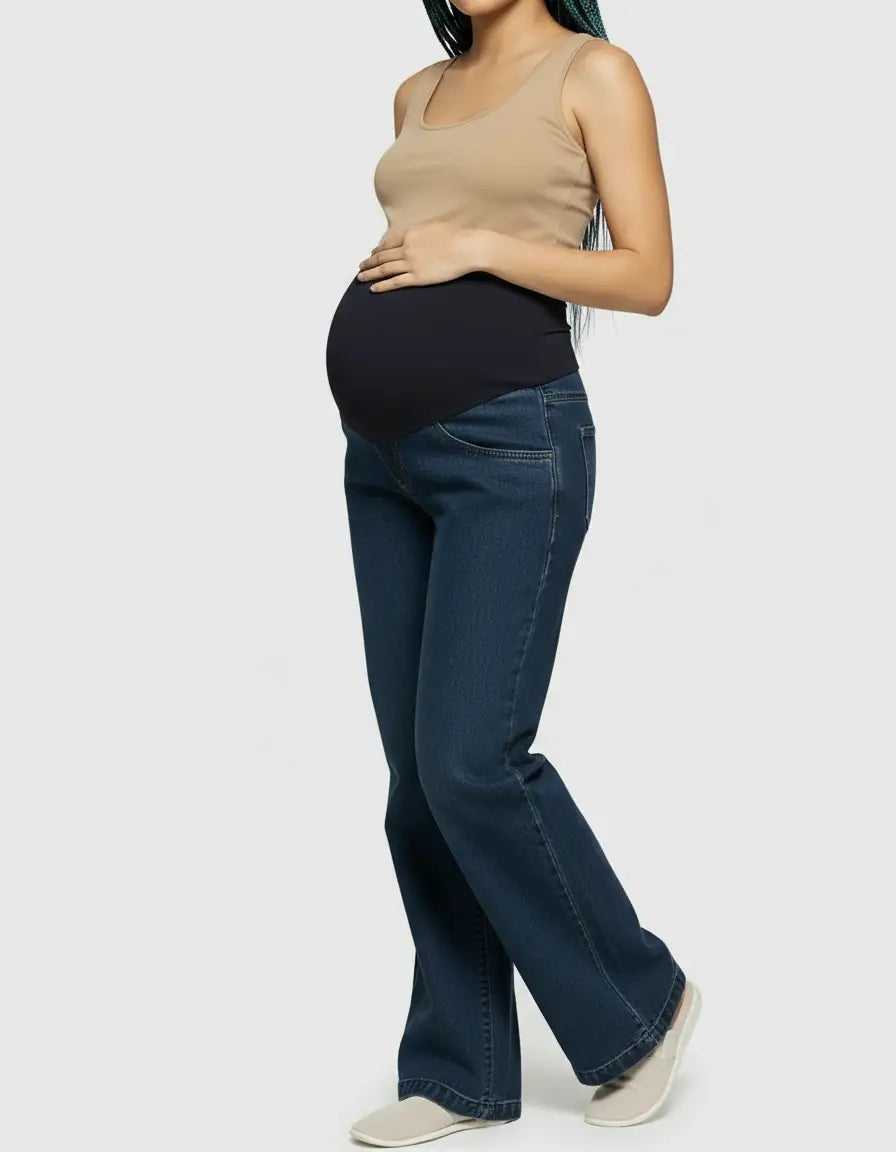 Maternity model in dark wash wide-leg jeans with a black elastic belly band and a beige tank top.