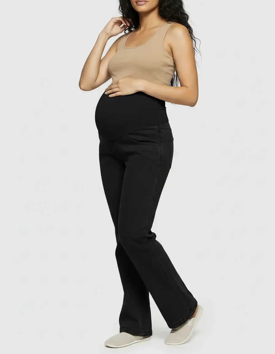Maternity model wearing black wide-leg jeans with an elastic over-the-bump panel and a beige tank top.
