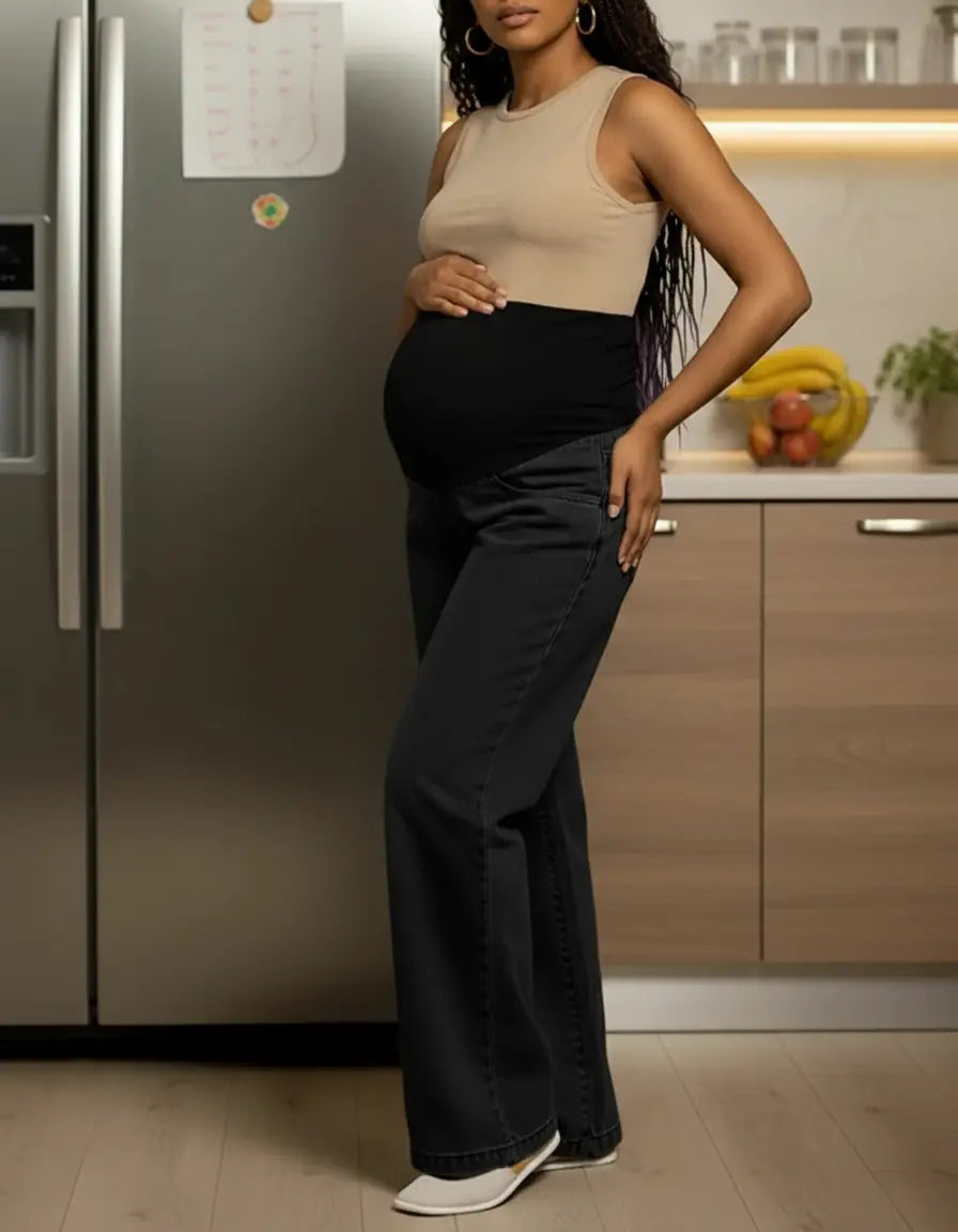 Pregnant woman in black wide-leg maternity jeans with elastic waist and a beige top.