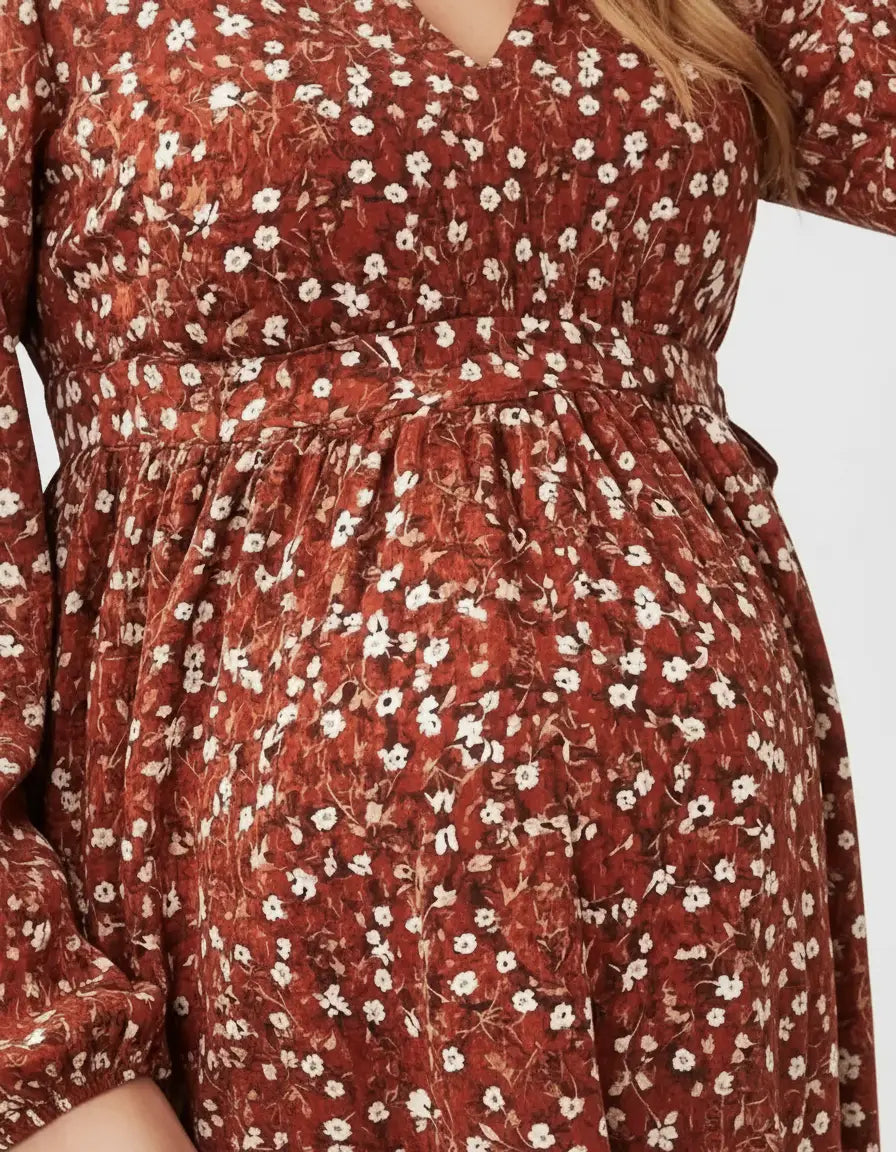 Close-up of a pregnant woman wearing a rust-colored floral print maternity top with a tie waist.
