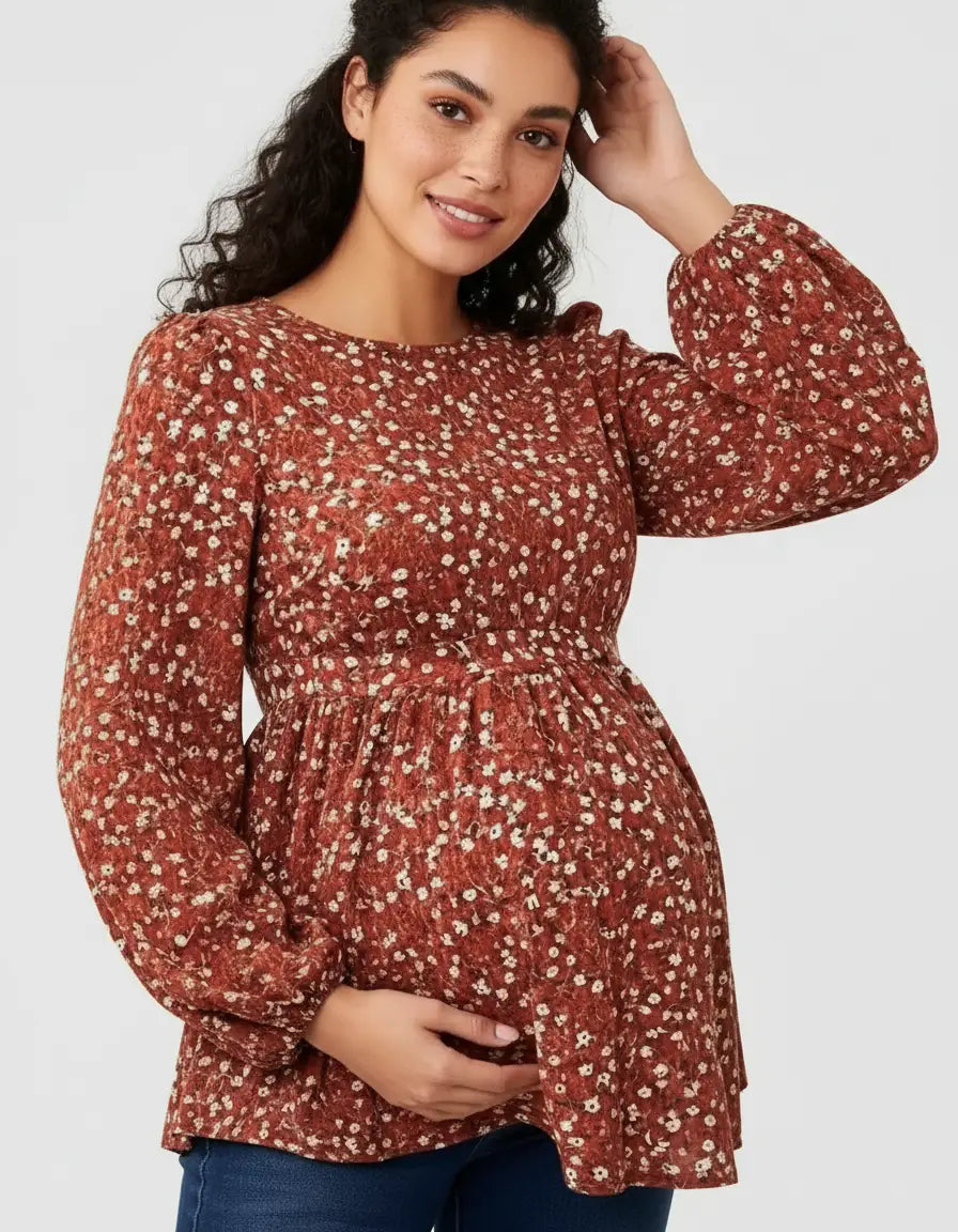 Maternity top in rust floral print with long puff sleeves and tie waist, worn by a smiling pregnant woman.