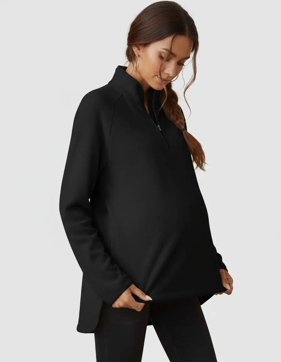 Black half-zip long sleeve maternity top with a stand collar and relaxed fit, shown on a pregnant model.