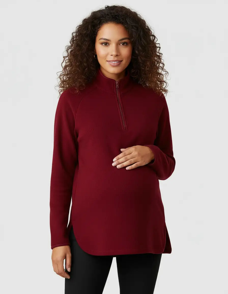 Maternity model in a red half-zip long sleeve top with a stand collar and side slits, designed for comfort.