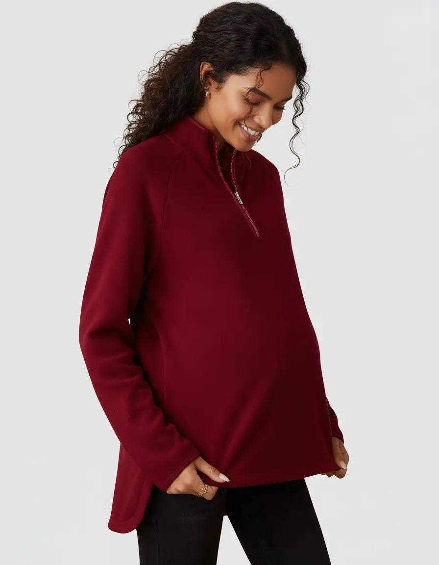 Smiling pregnant woman in a relaxed-fit burgundy half-zip long sleeve maternity top.