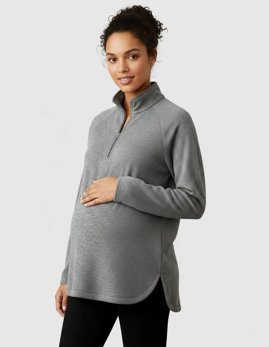 Pregnant woman in a gray soft knit half-zip long sleeve maternity top with a stand collar and side slits.