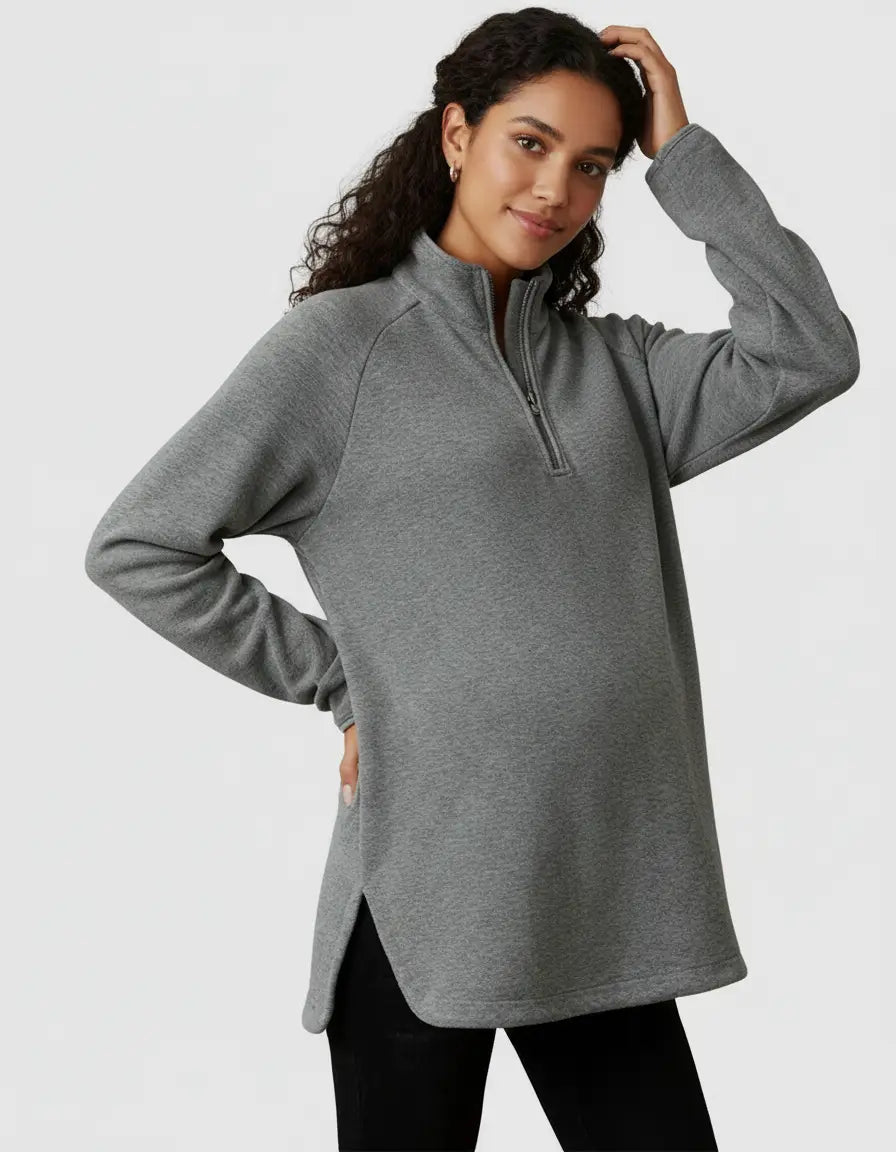 Maternity model wears a gray half-zip long sleeve top with side slits, showcasing its relaxed fit.