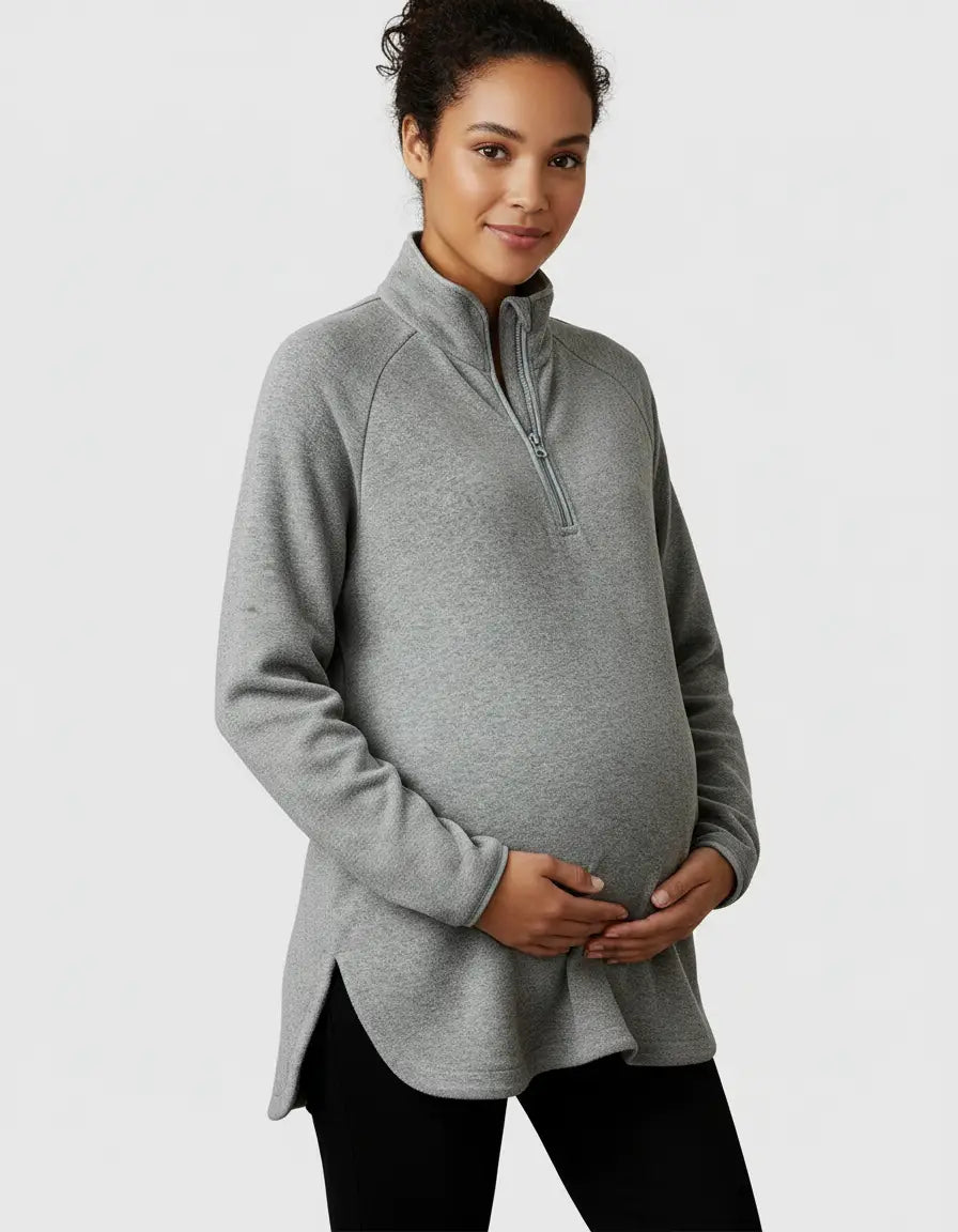 Pregnant woman in a gray soft knit half-zip long sleeve maternity top with a stand collar and side slits.