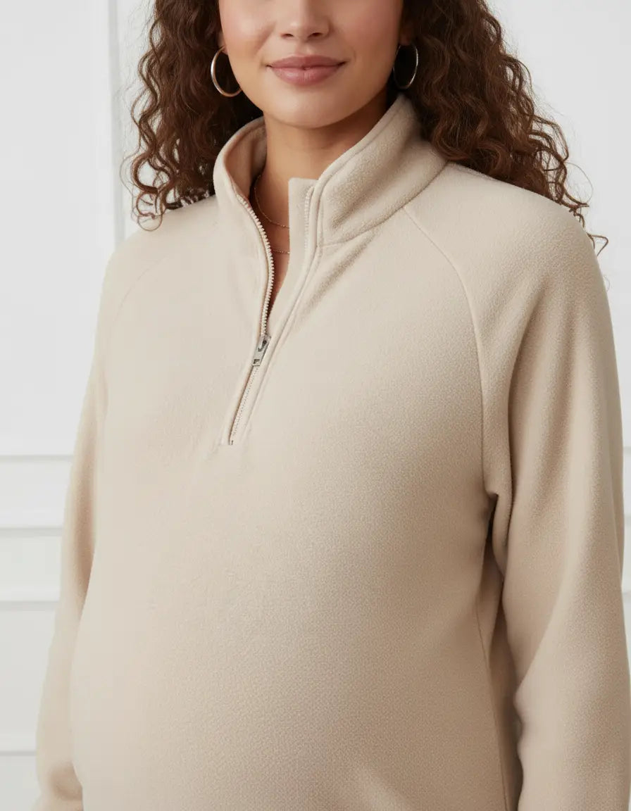Maternity model wearing a beige fleece half-zip long sleeve top with a stand collar, designed for comfort.