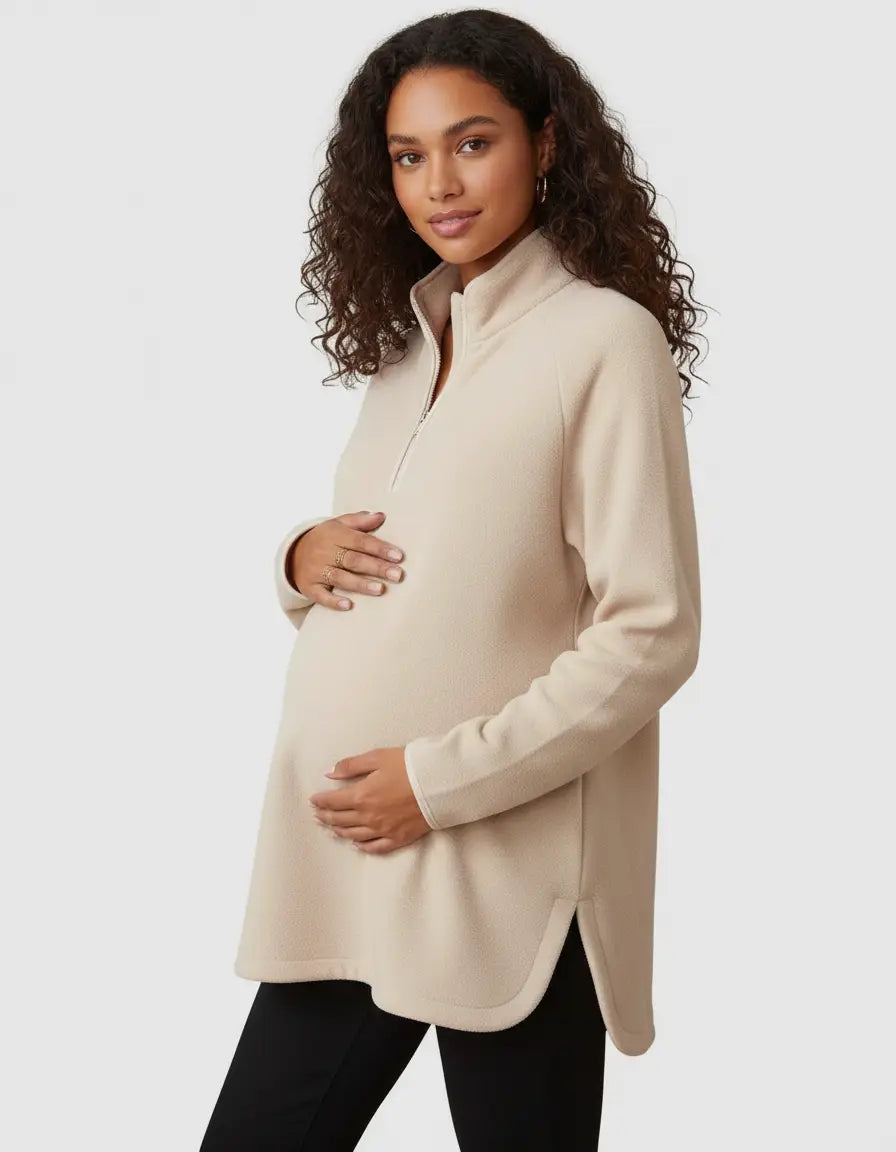 Pregnant woman in a beige soft knit half-zip long sleeve maternity top with side slits.