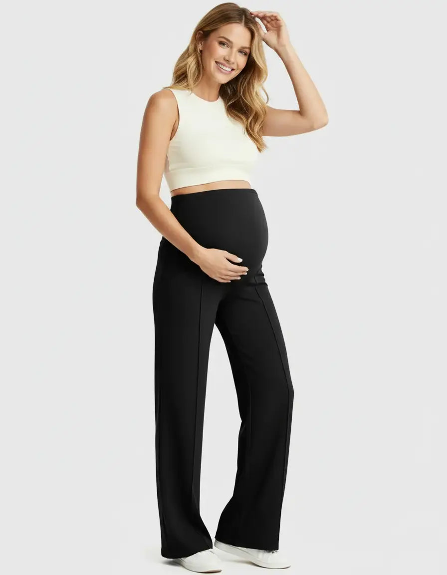 Smiling pregnant woman in black high-waist maternity pants with a relaxed fit and a white crop top.