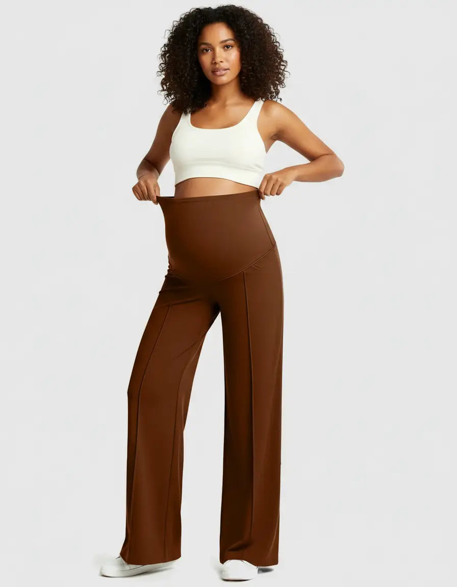 Woman in white crop top and brown high-waist maternity pants with relaxed fit and front seams.
