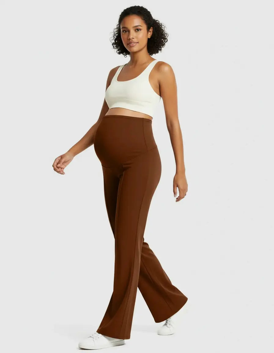 Pregnant woman in brown high-waist maternity pants with a relaxed fit and a white crop top.