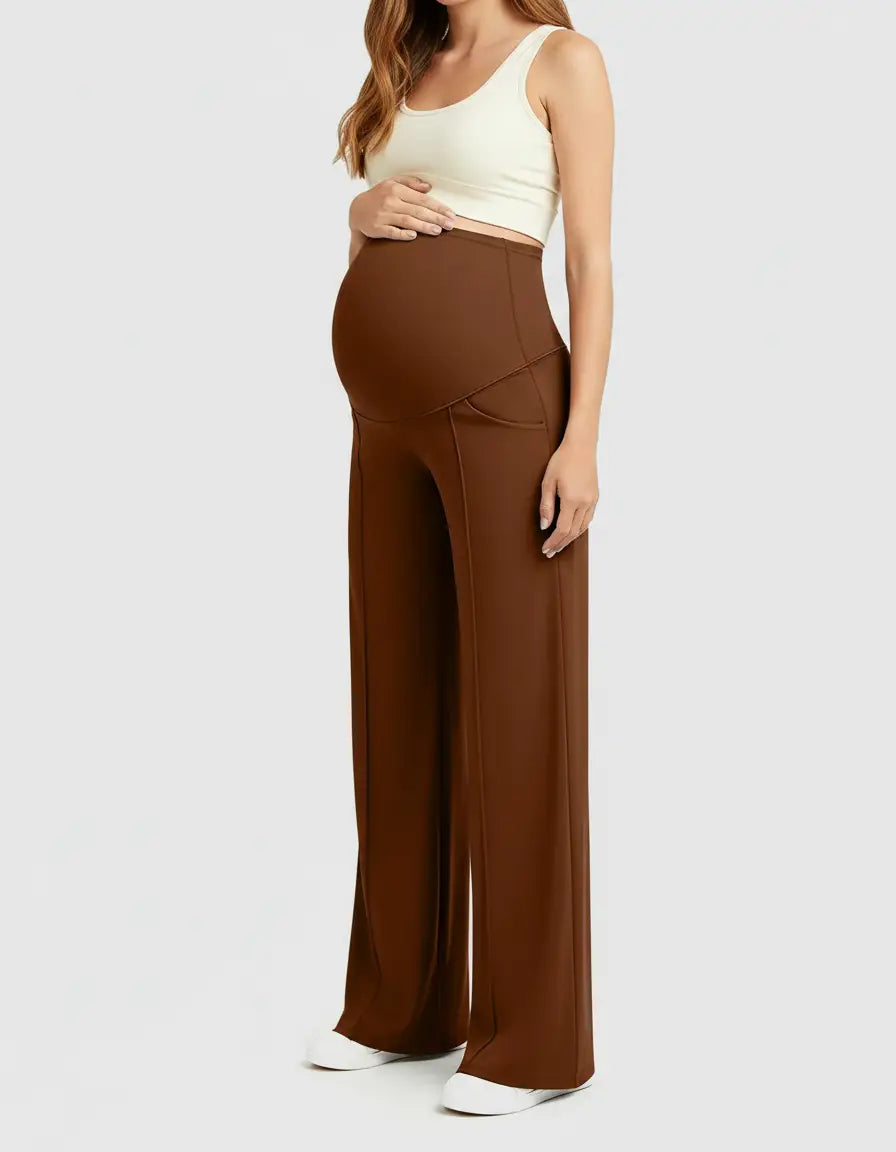Pregnant woman in brown high-waist maternity pants with a relaxed fit and a cream crop top.