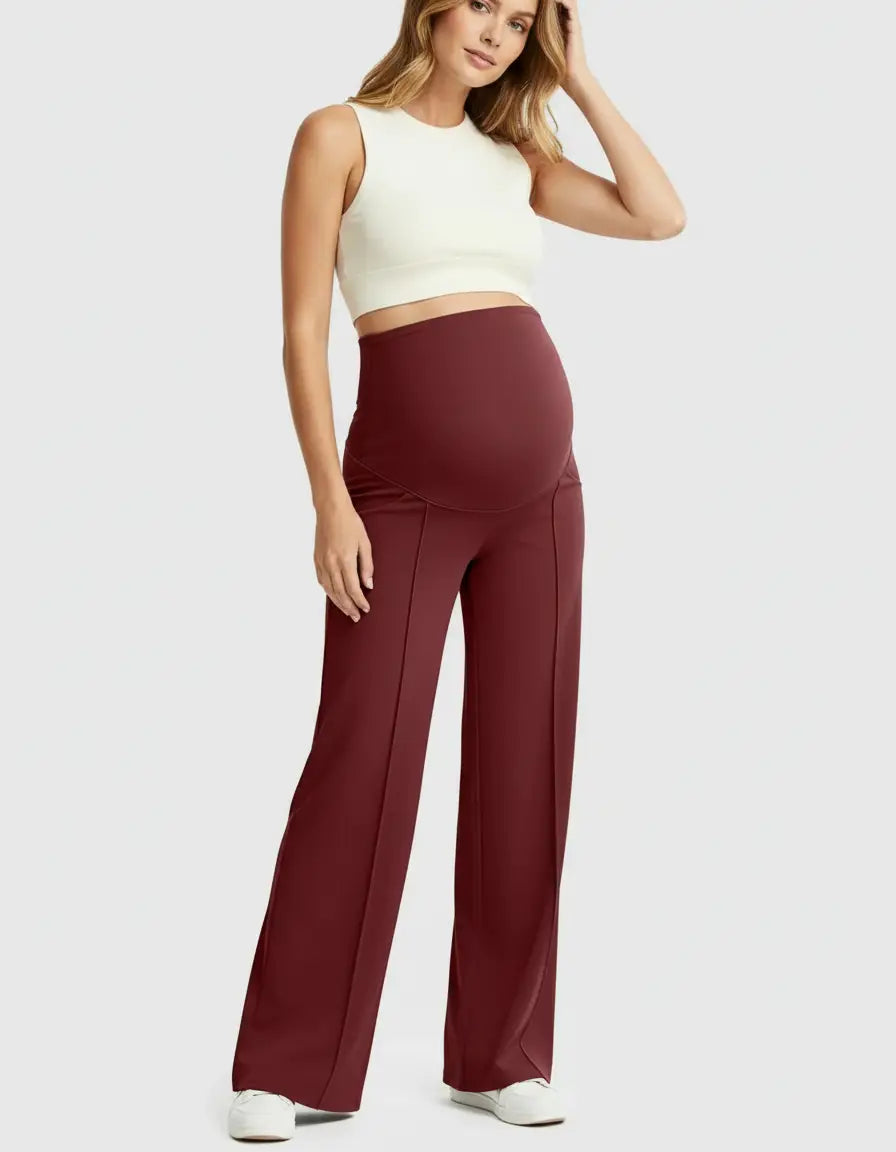Pregnant woman in comfortable, relaxed-fit burgundy high-waist maternity pants with a white crop top.